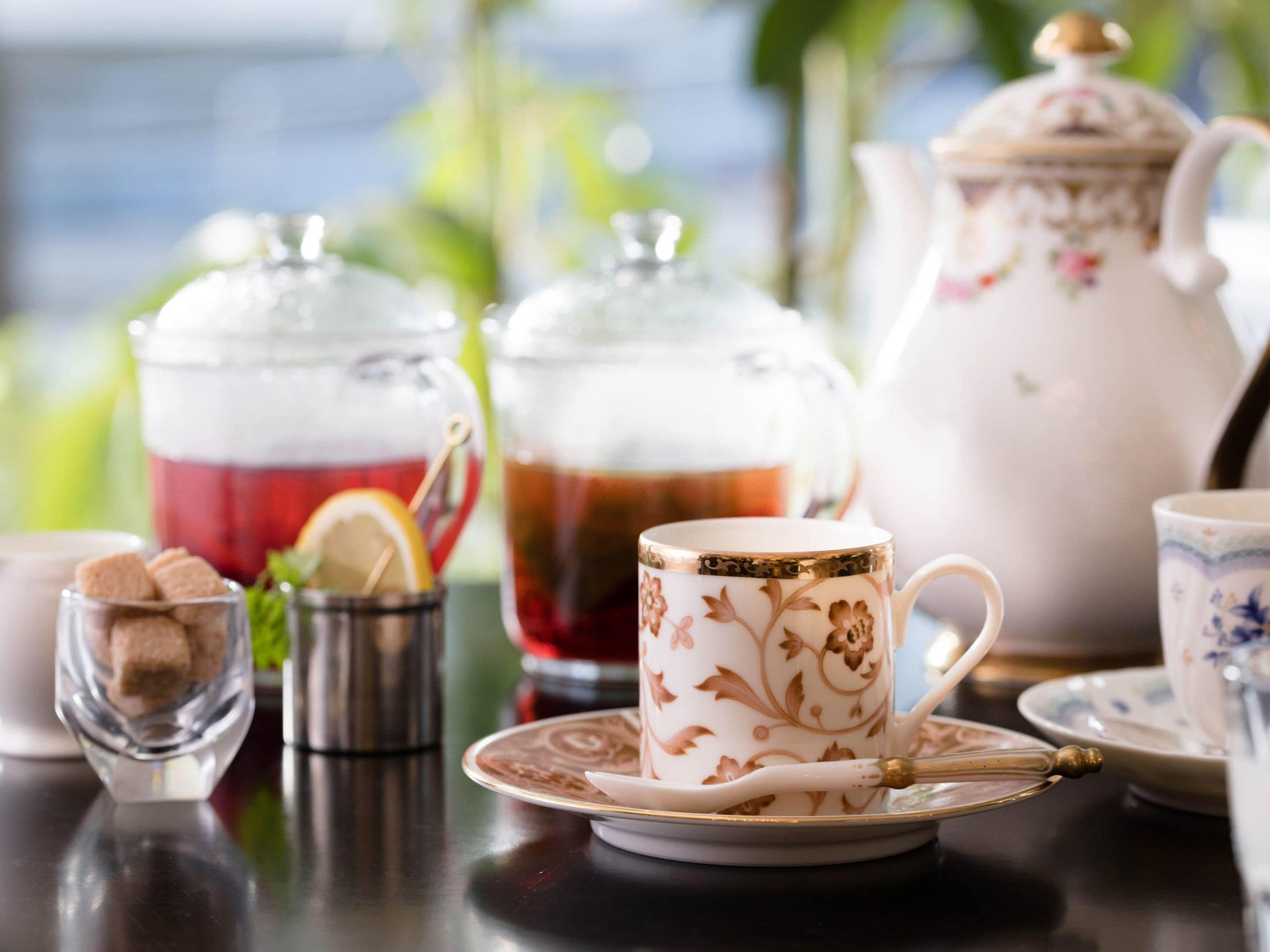 A table with a teapot, a teacup, and a glass pitcher.