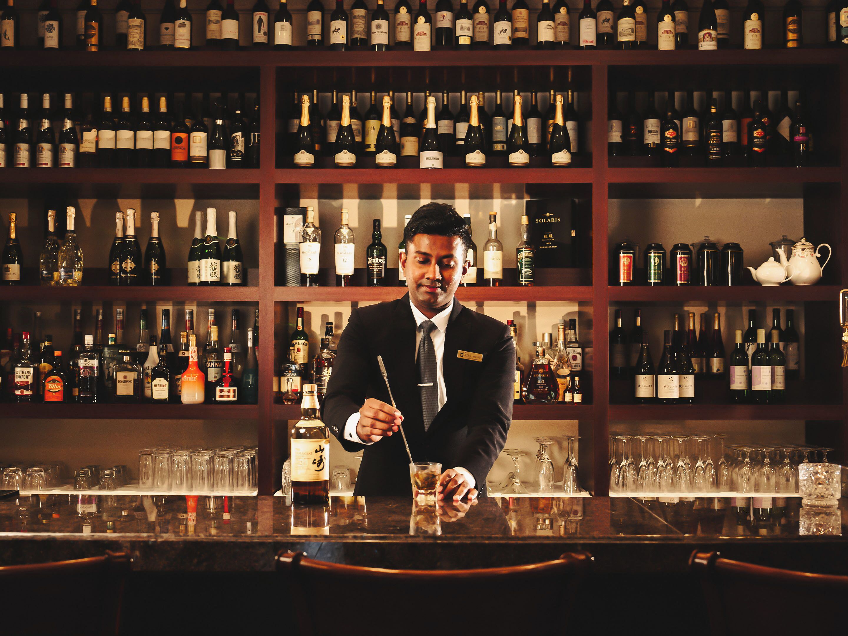 A bar with shelves of various liquor bottles and glasses.