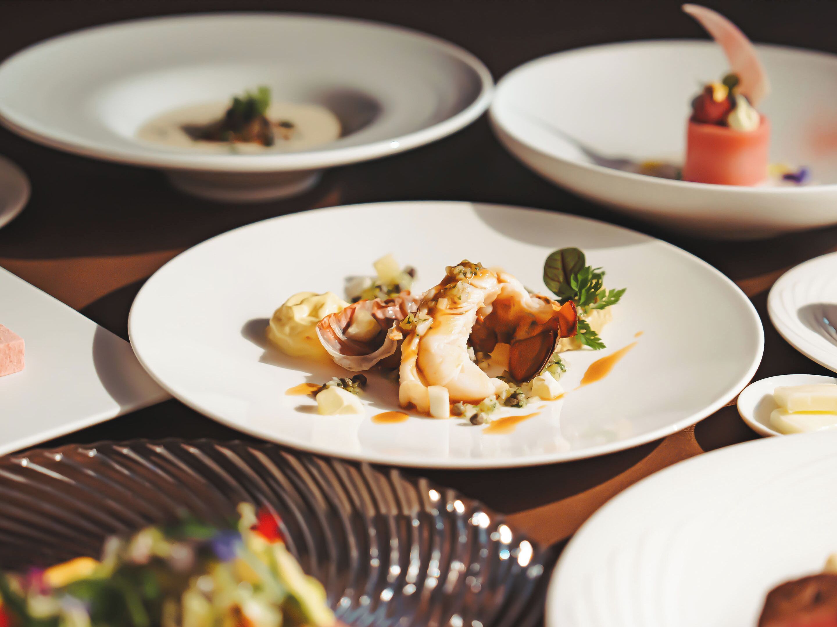 A dining table with various dishes, including seafood and vegetables, arranged on white plates.