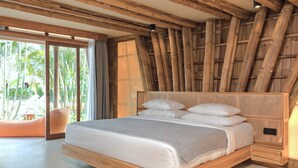 A spacious bedroom with a large bed, wooden ceiling beams, and a view of the outdoors. - Origin Lombok (Kuta)