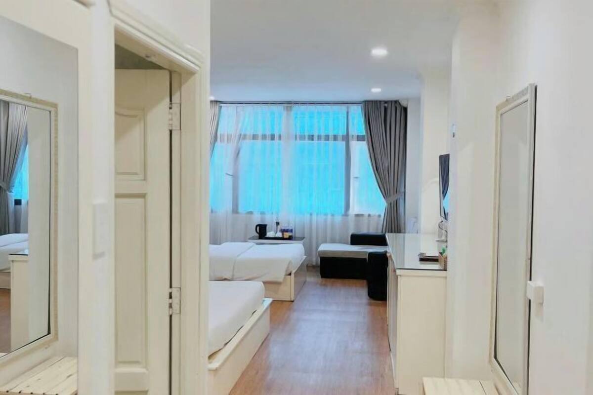 Une chambre d’hôtel avec un lit, un bureau, une chaise et une fenêtre avec des rideaux.