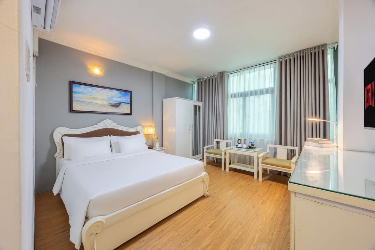 Une chambre d’hôtel avec un grand lit, un bureau avec une chaise, une télévision et un tableau au mur.