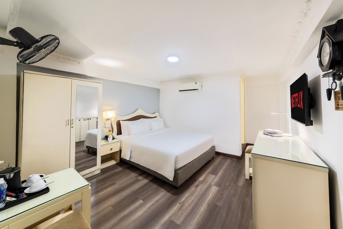 Une chambre d’hôtel équipée d’un lit, d’une table de chevet, d’une lampe et d’un téléviseur fixé au mur.