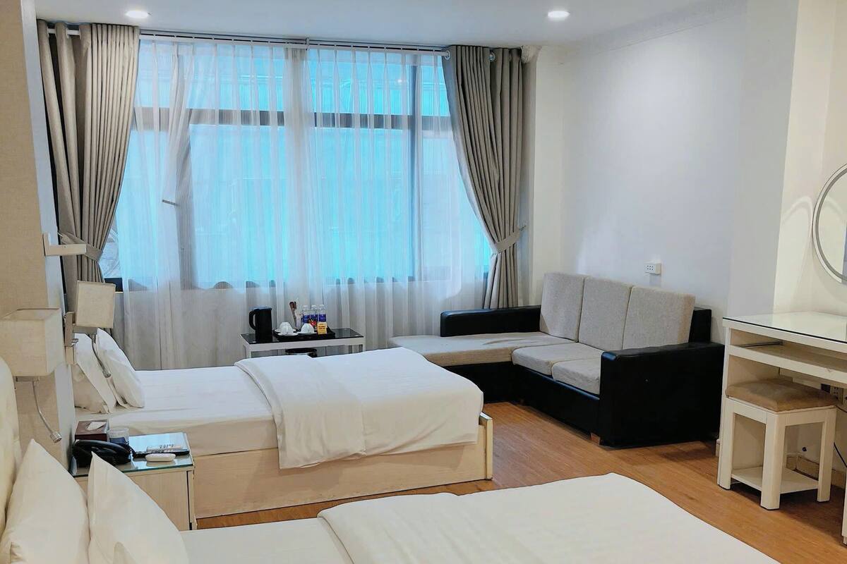 Une chambre d’hôtel avec deux lits, un bureau, une chaise et une fenêtre avec des rideaux.