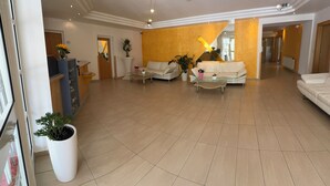 A spacious living area with a large sofa set, a coffee table, and potted plants. - Strandhotel Faak (Finkenstein am Faaker See)