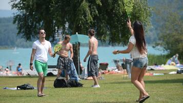Guests can enjoy a game of outdoor fun on the lush grassy field overlooking a serene lake and surrounding trees.