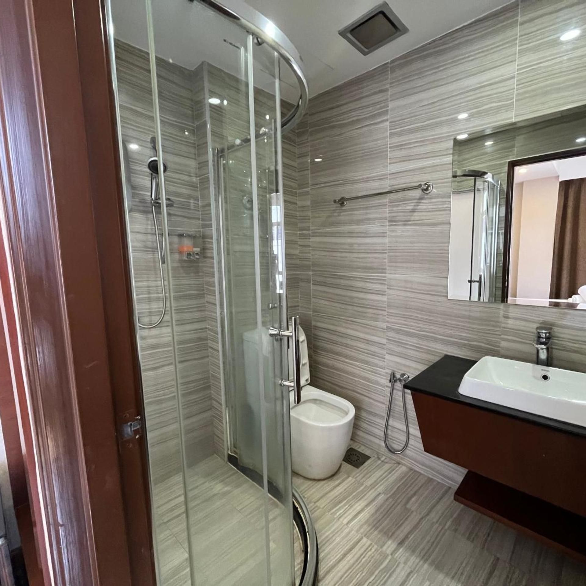 Ein modernes Badezimmer mit einer Duschkabine, einer weißen Toilette und einem Waschtisch.