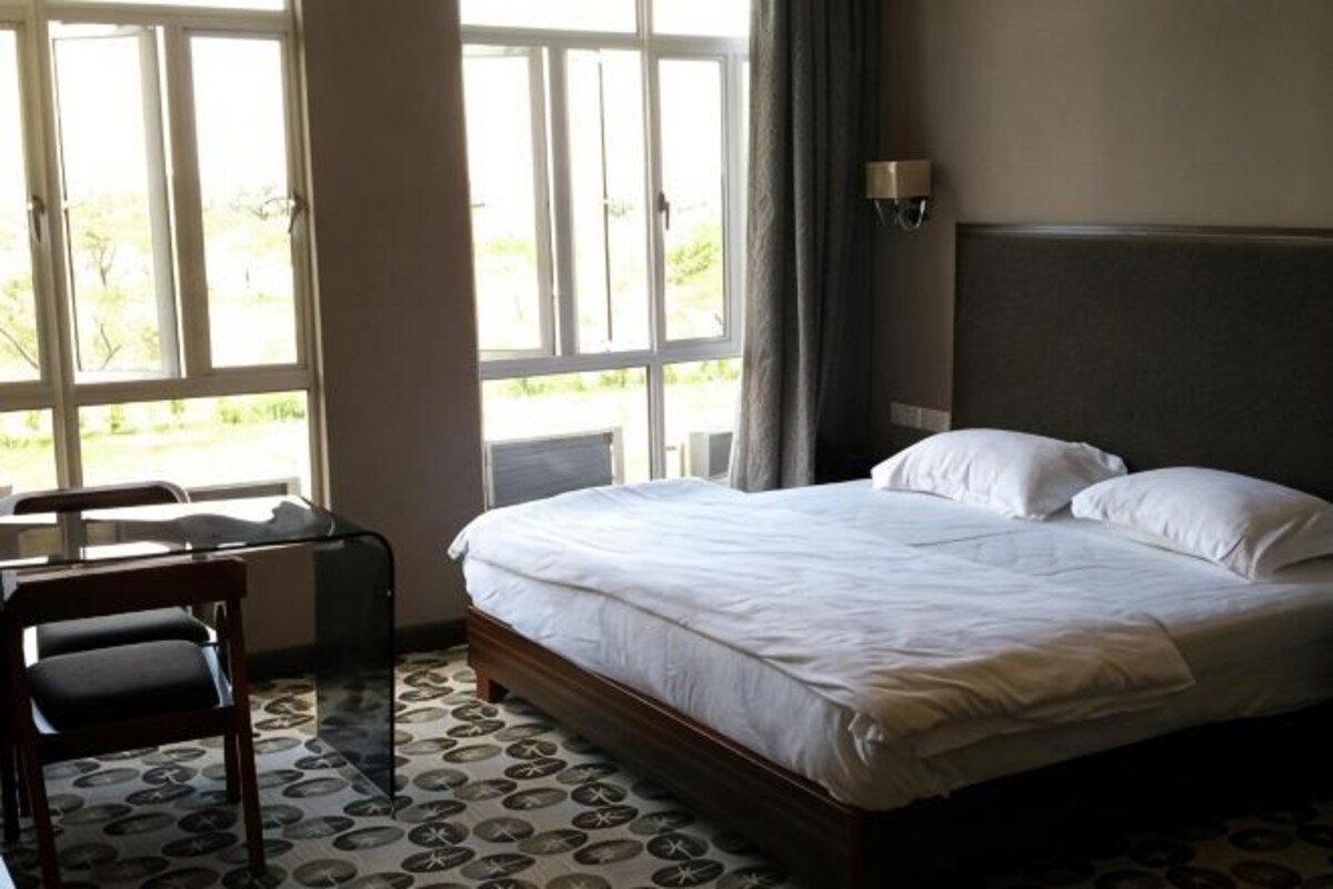 A hotel room with a bed, a desk, and a chair.