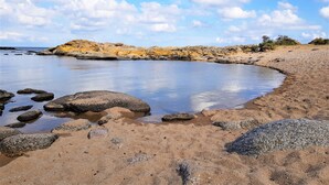 A beach with clear water, rocks, and a sandy shore. - Pyttegaarden Apartments (Gudhjem)
