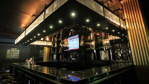 A bar with a modern design, featuring a large illuminated sign, a variety of bottles, and a bar counter. - Belviu Hotel Bandung (Bandung)