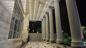 A covered walkway with columns and a tiled floor, leading to a building entrance. - Belviu Hotel Bandung (Bandung)