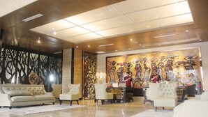 A lobby with a reception desk, two sofas, and a large mural on the wall. - Belviu Hotel Bandung (Bandung)