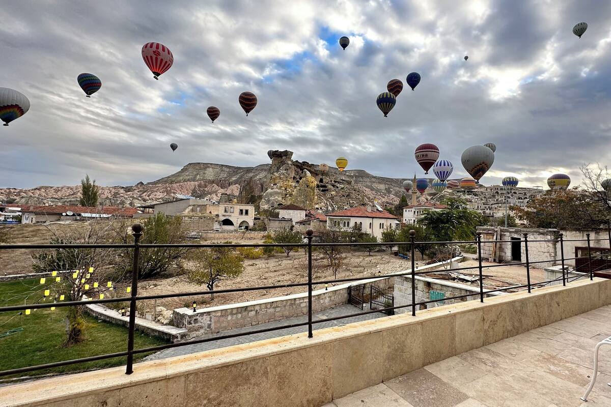 Un balcón con vistas a un pueblo y globos aerostáticos en el cielo.