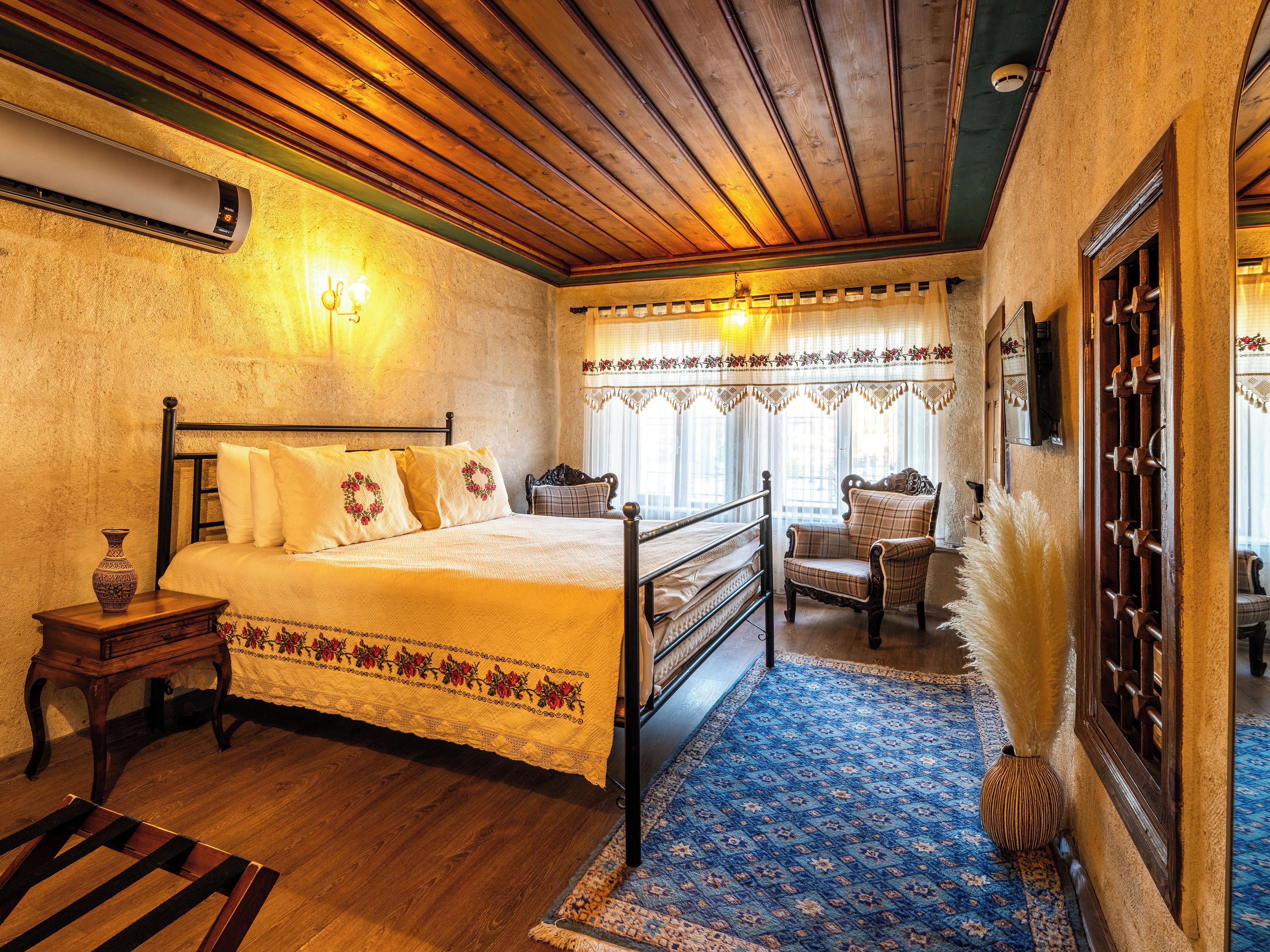 A traditional room with a bed, a chair, a small table, and a decorative vase.