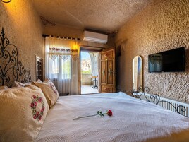 Un dormitorio con una cama, un televisor montado en la pared y una puerta que da a un espacio exterior.