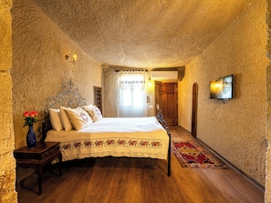 Ein Schlafzimmer mit einem hölzernen Bett, einem Nachttisch, einer Blumenvase und einem an der Wand befestigten Fernseher.