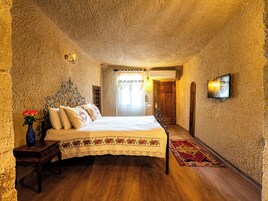 Un dormitorio con una cama de madera, una mesita de noche, un florero con flores y un televisor de pared.