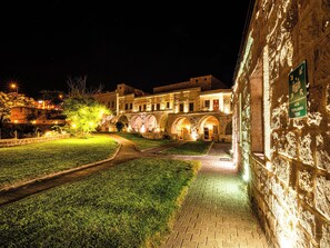 A historic building with illuminated arches and a paved courtyard. - Jacob's Cave Suites (Avanos)