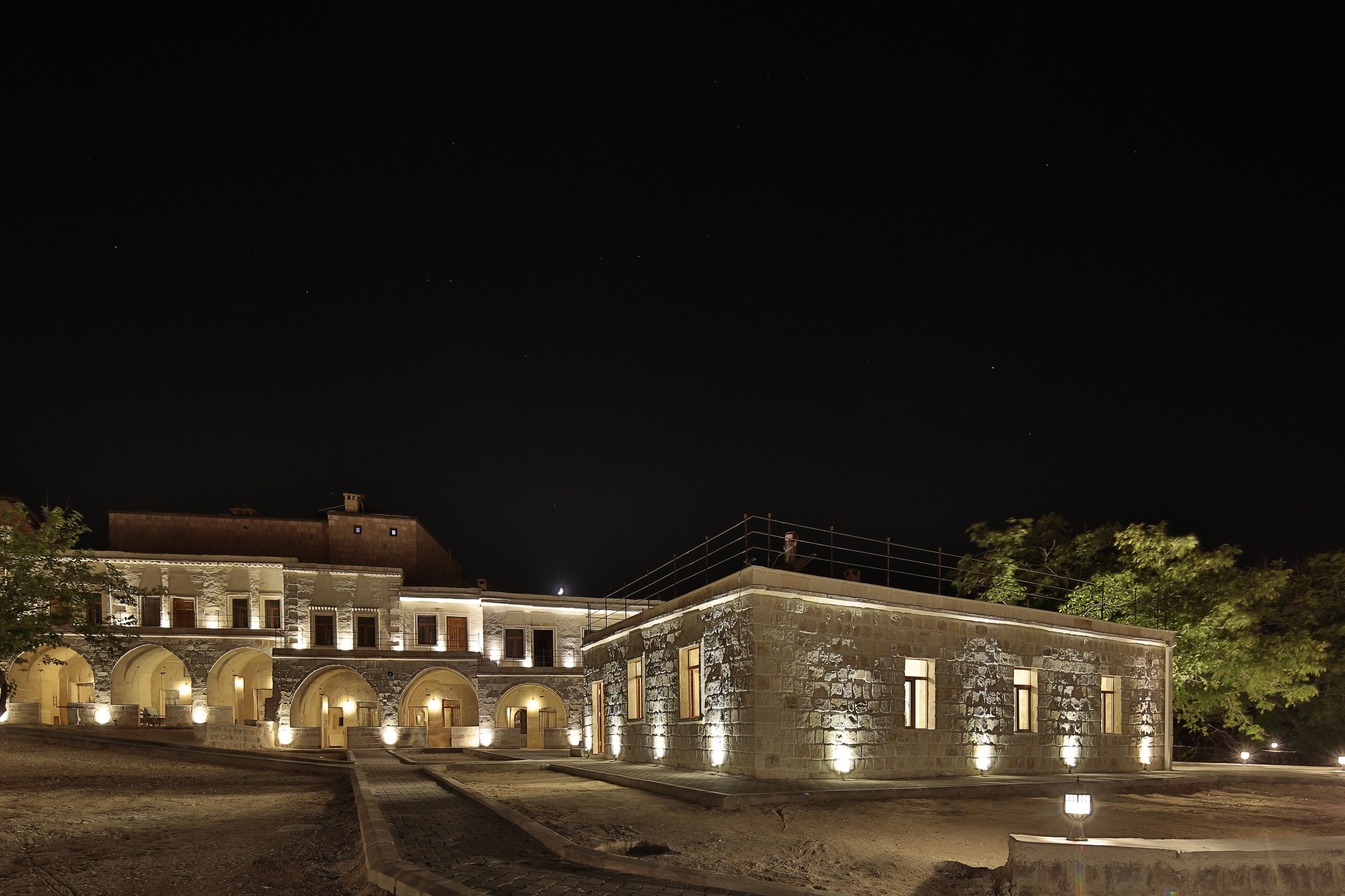 Een historisch gebouw met meerdere bogen en een binnentuin, verlicht in de nacht.