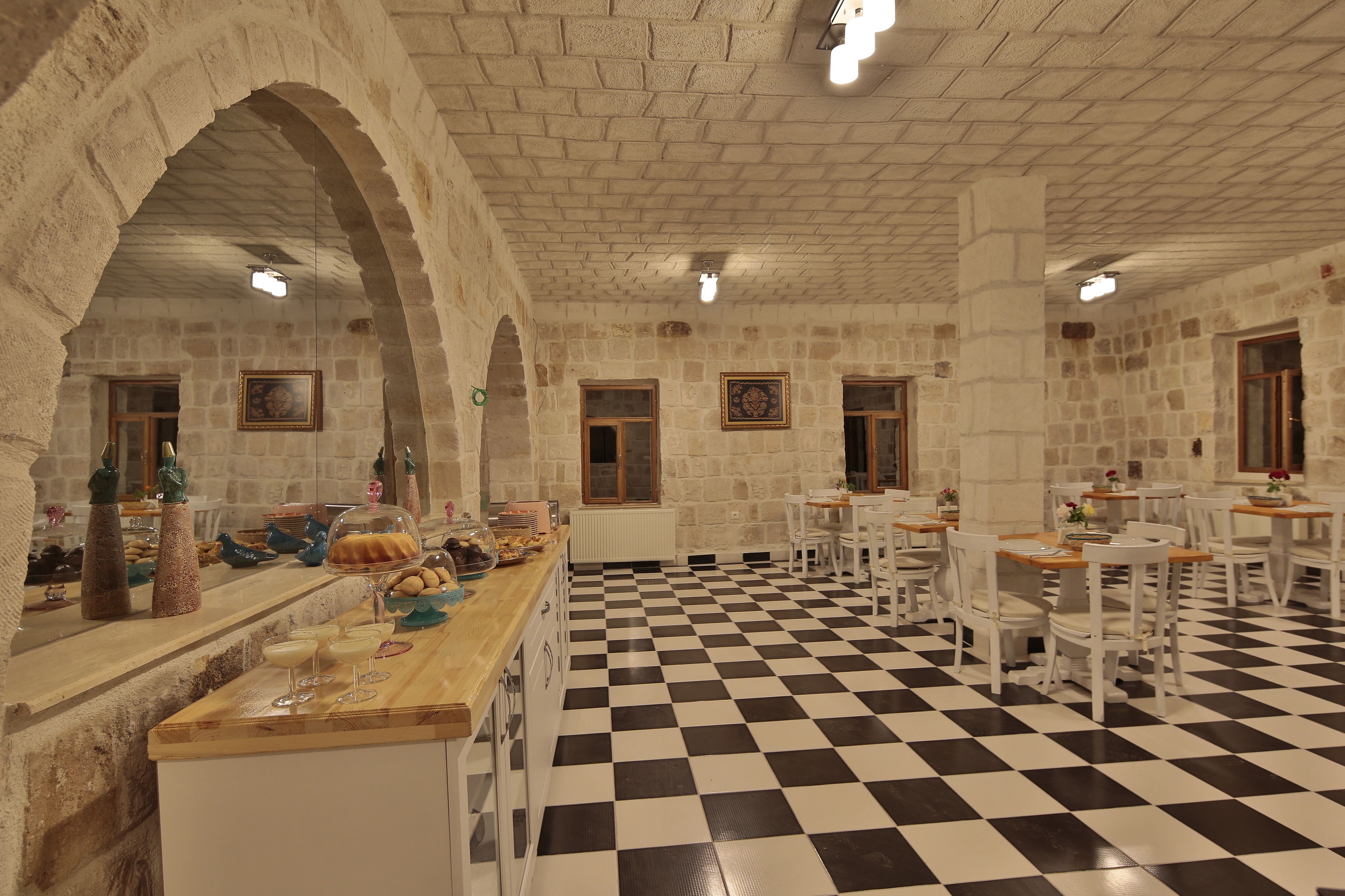 A restaurant with a checkered floor, stone walls, and white furniture.
