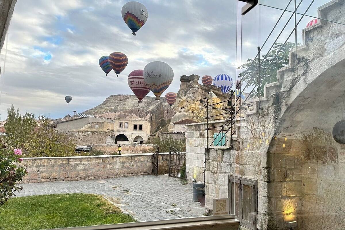 Un patio con muros de piedra, una reja y vistas a un edificio histórico con arcos.