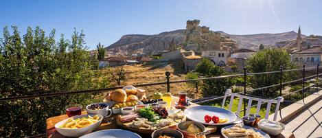 A table set with various dishes and a view of a historic town with a castle in the background.