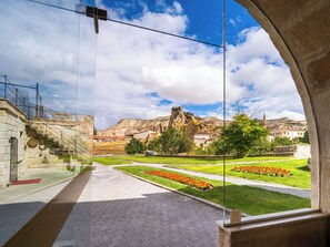 A courtyard with a clear view of a mountainous landscape, a stone building, and a flagpole. - Jacob's Cave Suites (Avanos)