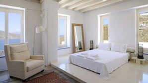 Une chambre à coucher avec un lit, une chaise, un miroir et de grandes fenêtres.
