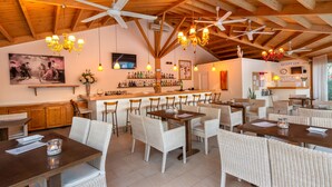 Een restaurant met houten balken, rieten stoelen en een bar.