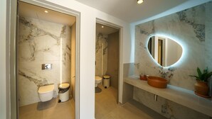 A bathroom with marble walls, a sink with a round mirror, and a toilet.