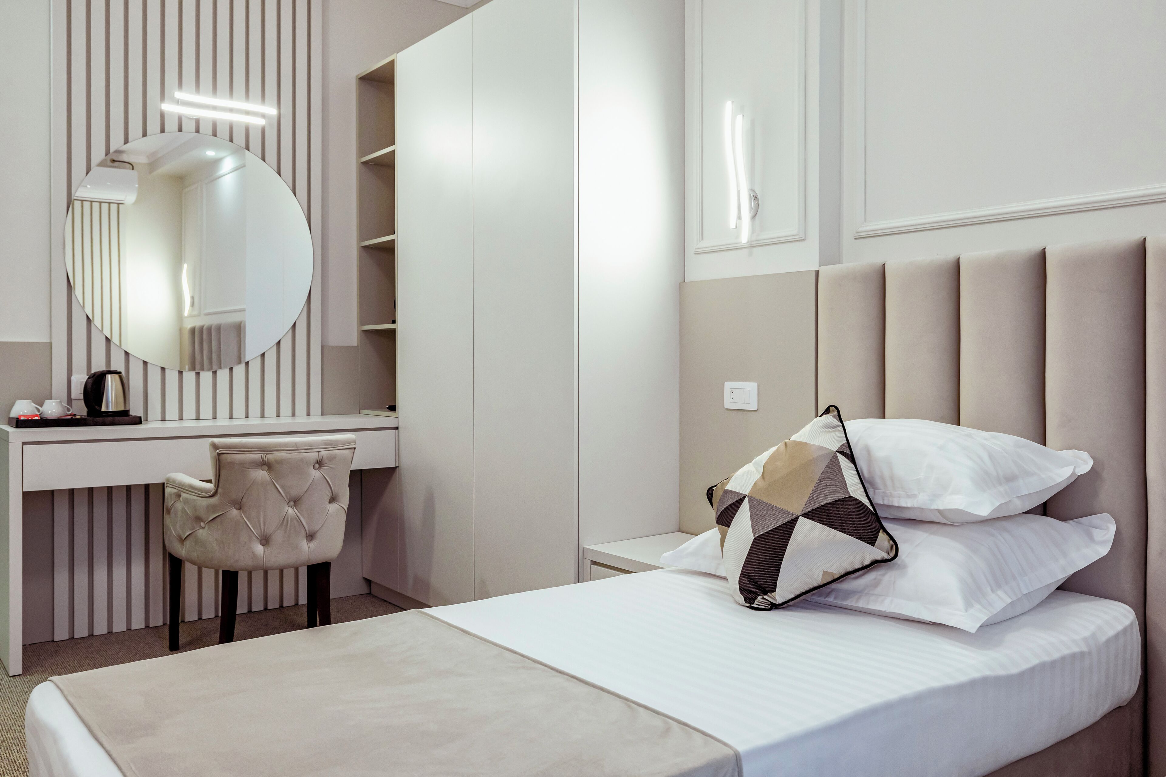 Een moderne slaapkamer met een bed, een bureau, een stoel en een grote spiegel.
