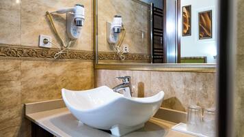 Un baño con un lavamanos blanco tipo lavabo, un espejo y un secador de pelo fijado a la pared.