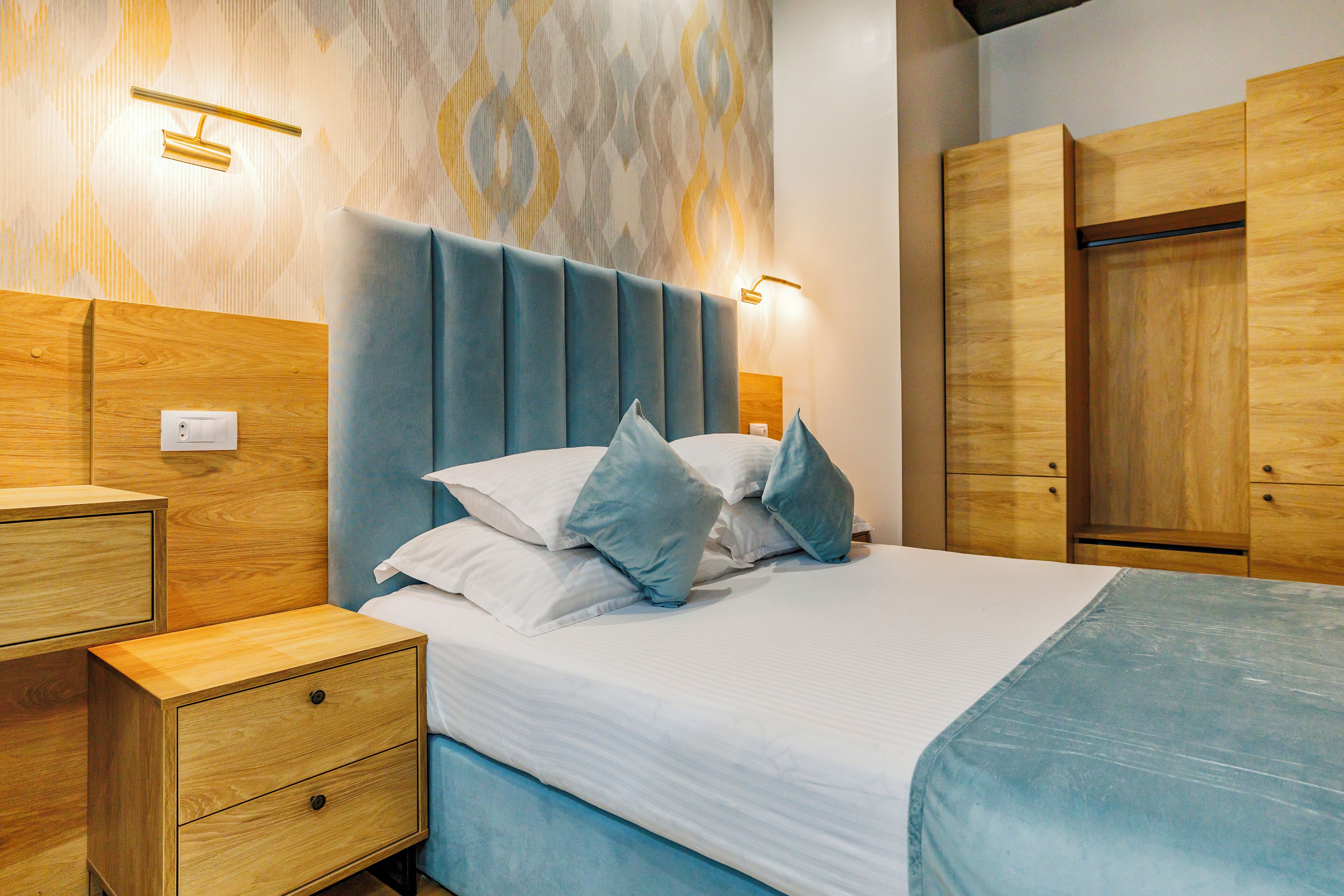 A modern bedroom with a bed, nightstands, and a wardrobe.