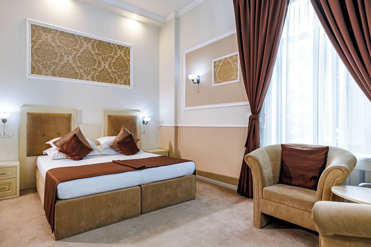 Una habitación de hotel con una cama grande, un sofá, una mesita y un espejo.