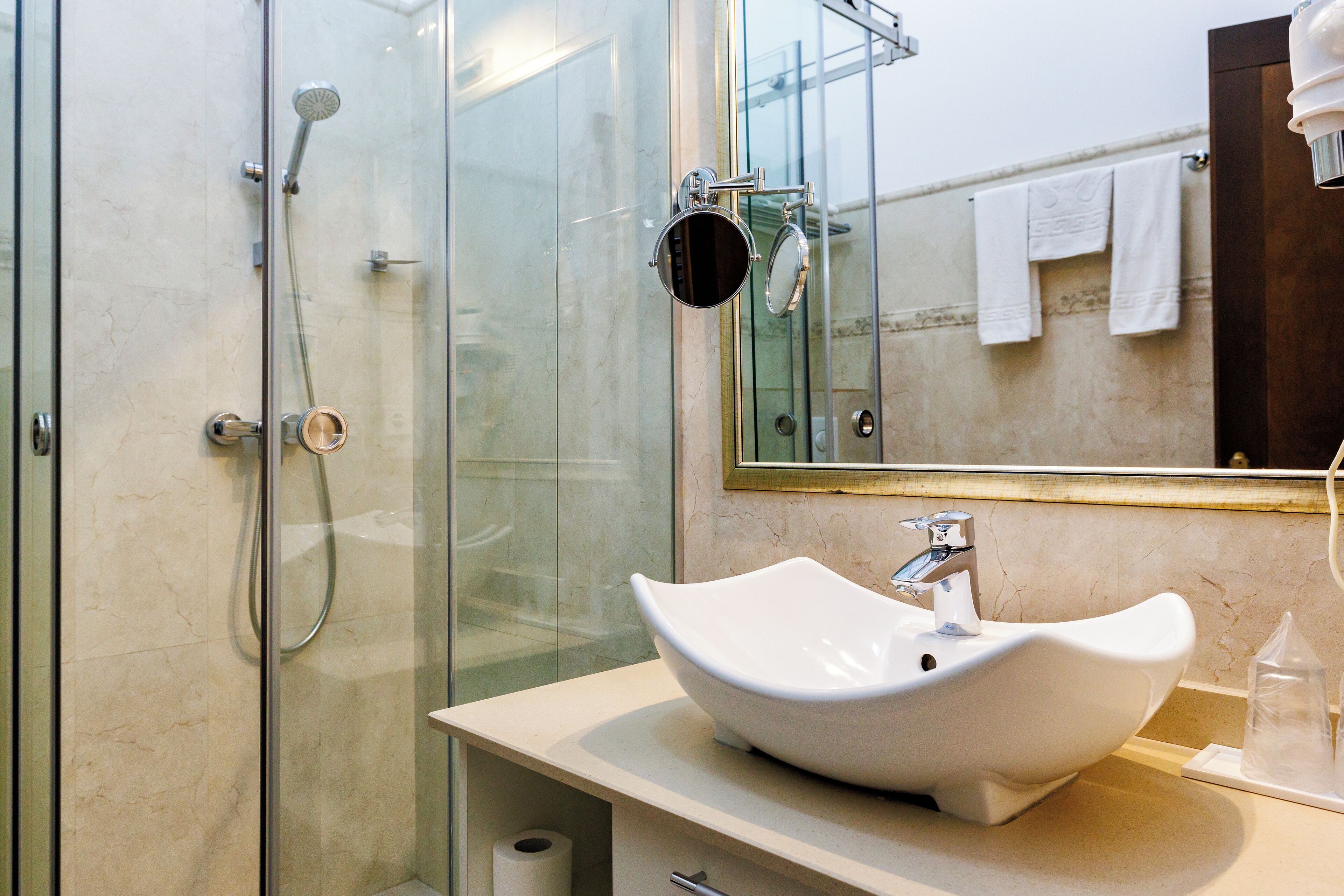 A modern bathroom with a glass-enclosed shower, a white sink, and a mirror above the sink.