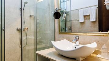 A modern bathroom with a glass-enclosed shower, a white sink, and a mirror above the sink.
