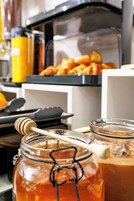 Una encimera de cocina con un tarro de miel y un cucharón de miel, un tarro de vidrio con miel y un recipiente con jarabe.
