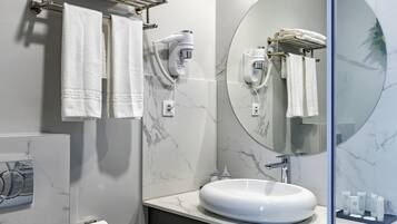 A modern bathroom with a marble sink, towel rack, hairdryer, and a large mirror.
