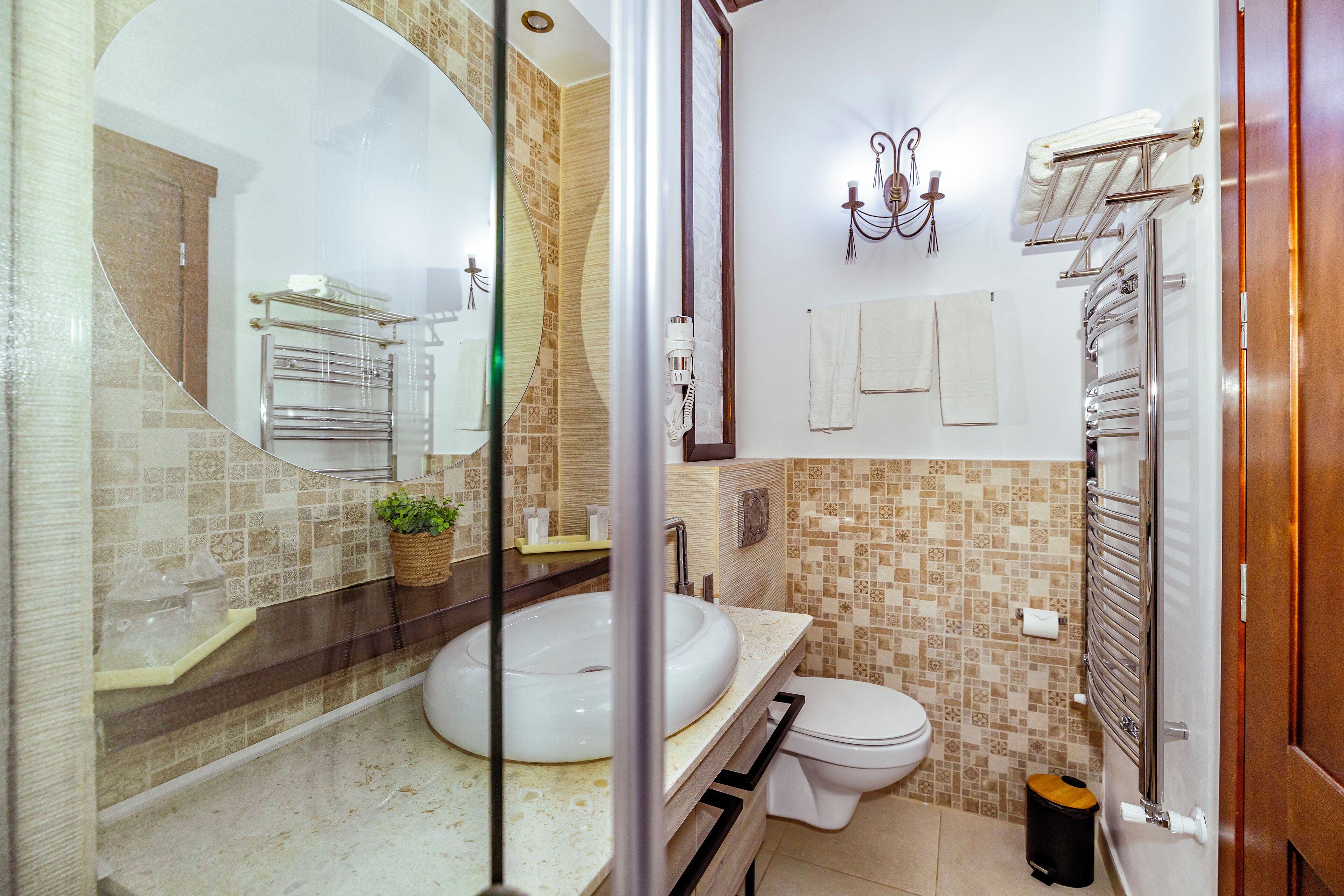 A bathroom with a round sink, a toilet, a towel rack, and a mirror.
