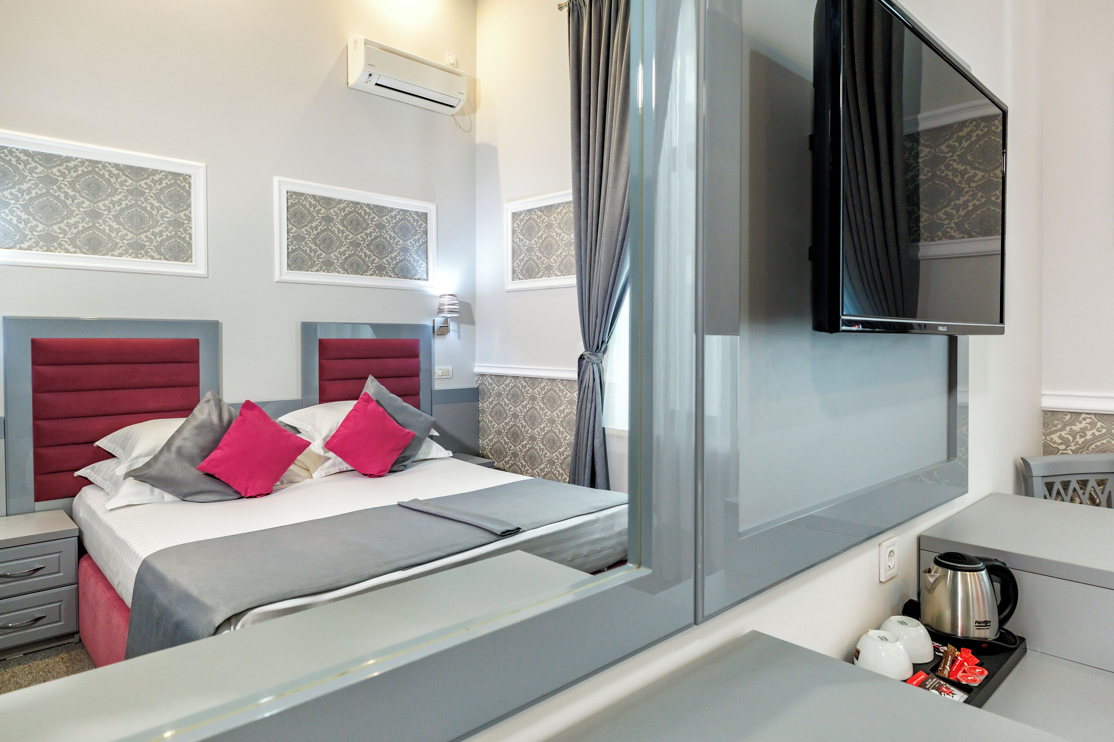 Een moderne hotelkamer met een groot bed, een flatscreen televisie, een koffiezetapparaat en een kleine tafel met een waterkoker.