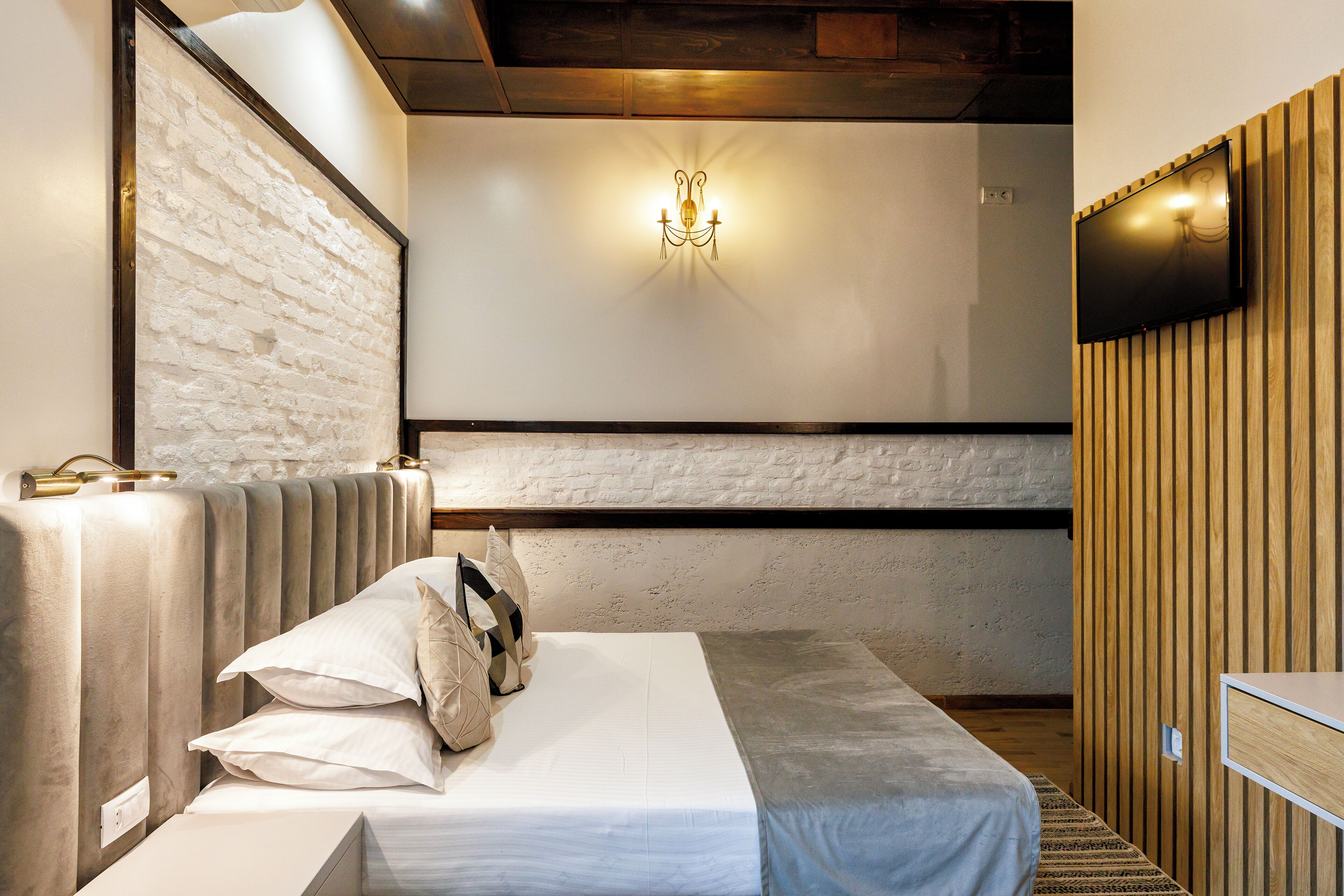 A modern bedroom with a bed, a wall-mounted TV, and a unique light fixture.