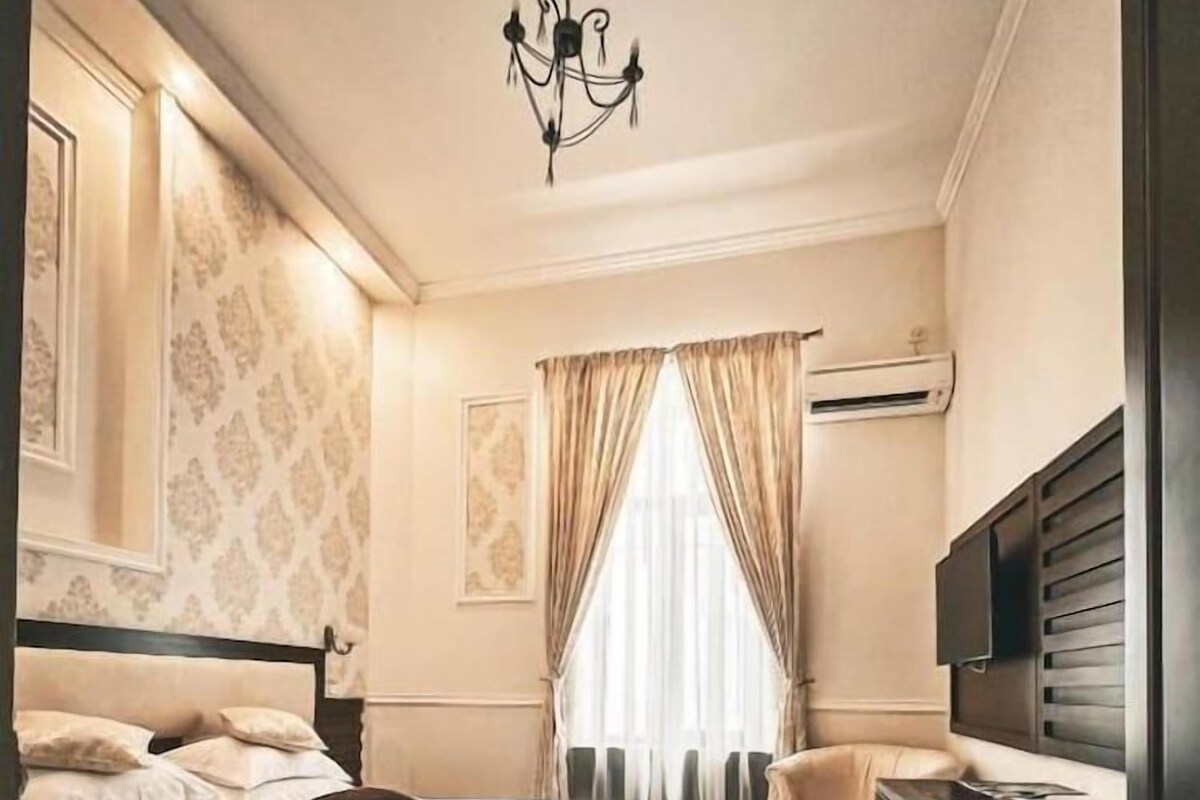 A bedroom with a bed, a chair, a dresser, and a television.