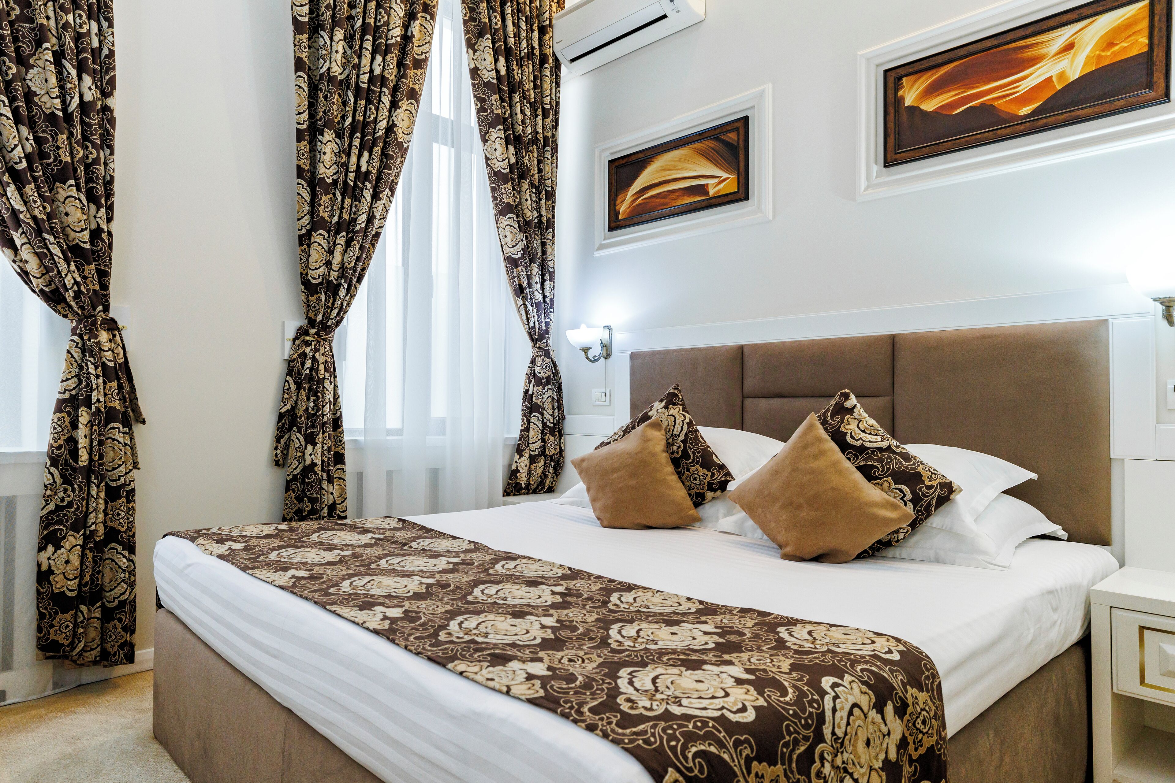 A neatly made bed with a patterned bedspread, two decorative pillows, and a headboard.