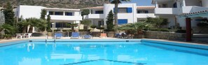 Una piscina al aire libre, sombrillas, sillones reclinables de piscina