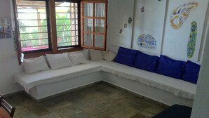 Ein Zimmer mit einer eingebauten Sitzbank, einem fenster mit Vorhängen und einem Fliesenboden.