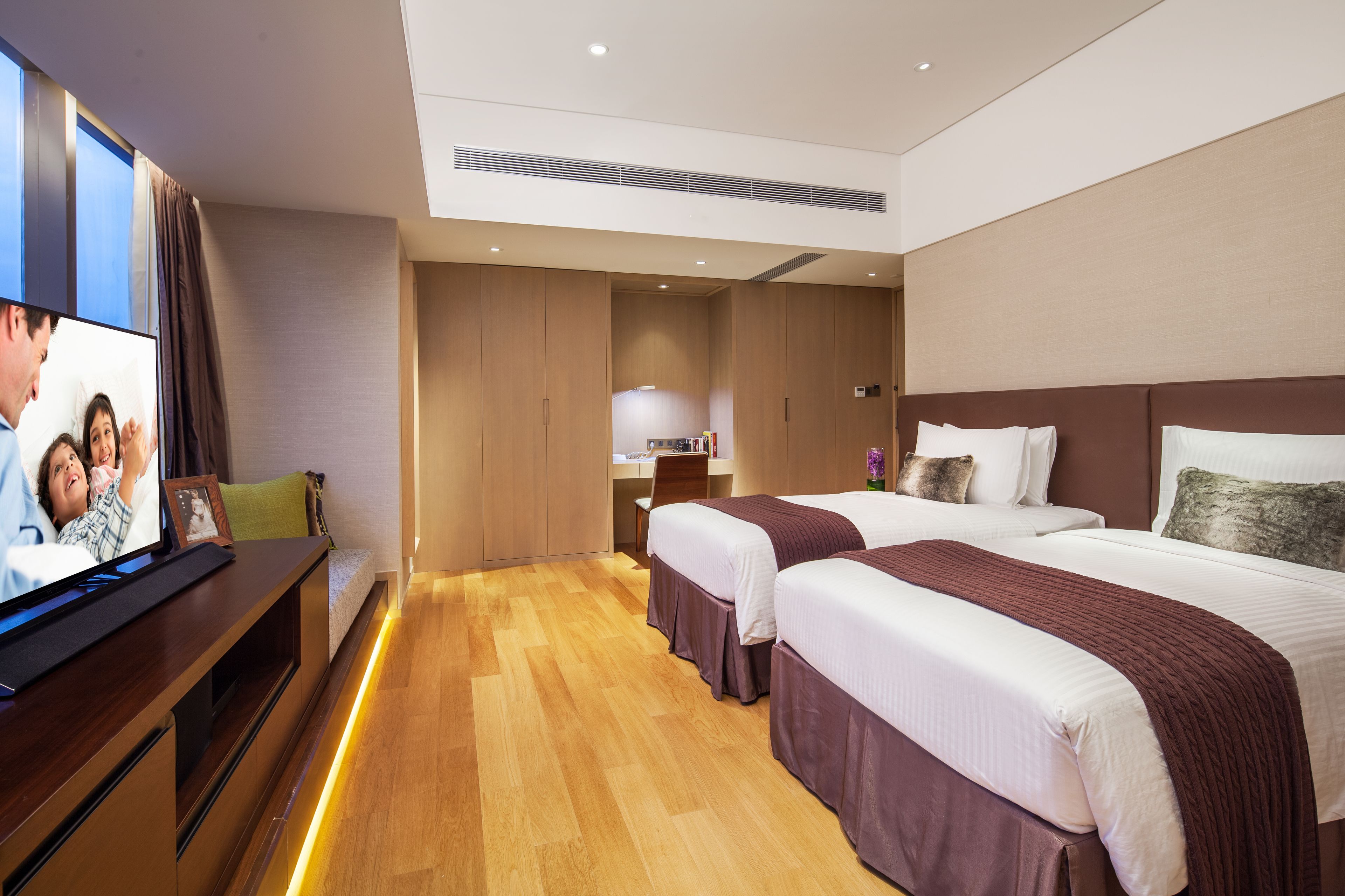 A hotel room with two beds, a television, a desk, and a wardrobe.