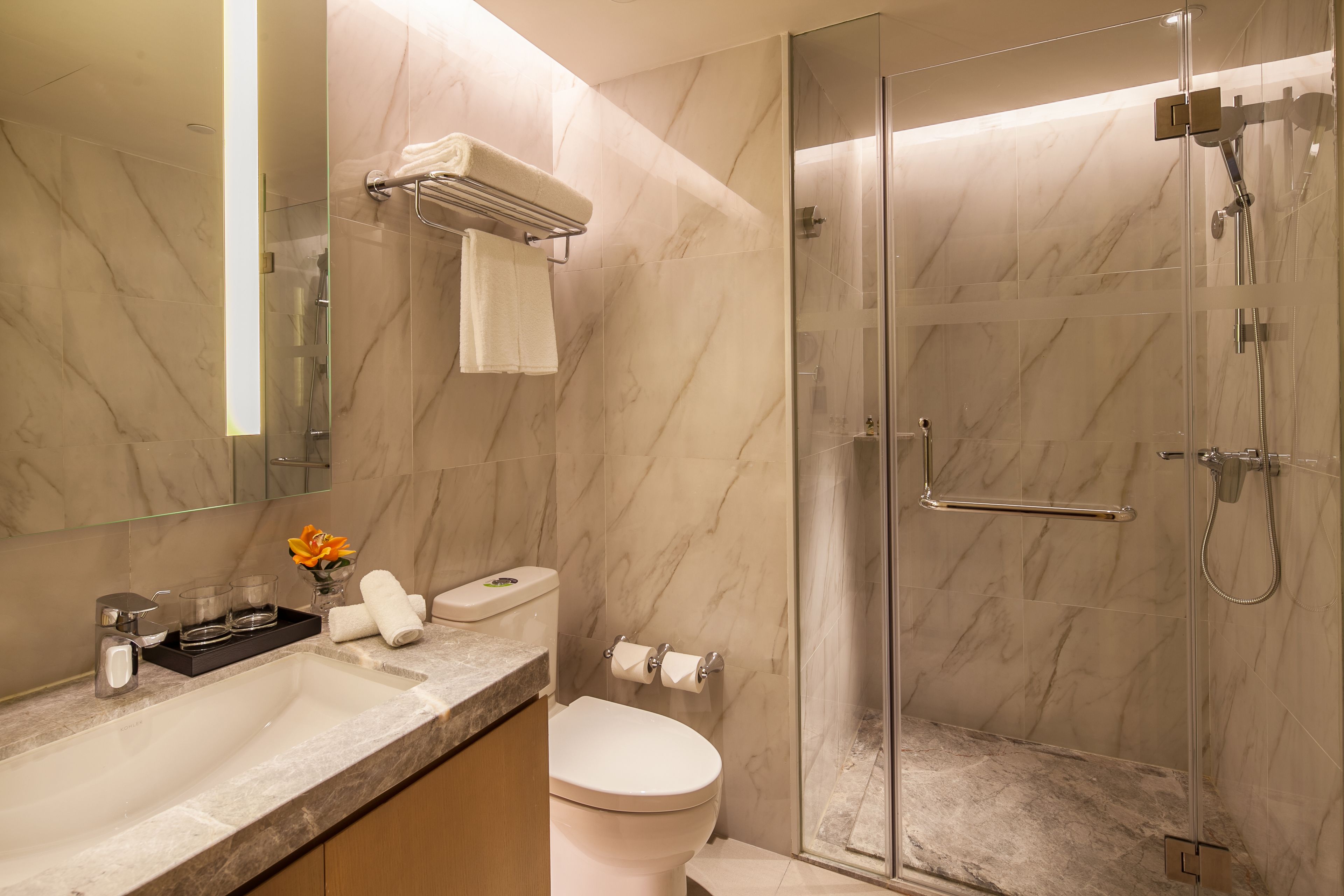 A modern bathroom with a marble sink, toilet, and glass-enclosed shower.