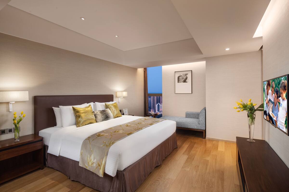 Een moderne hotelkamer met een groot bed, nachtkastjes, een televisie en uitzicht op de stad.