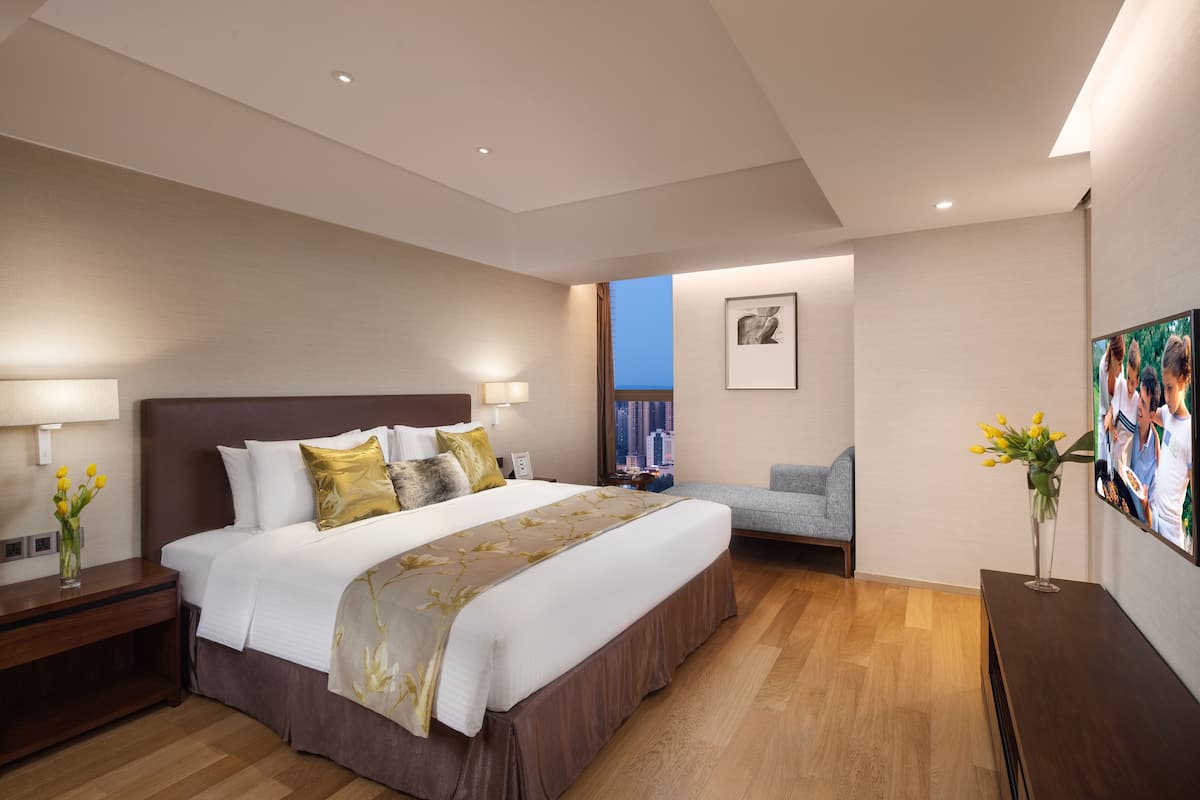 Ein modernes Hotelzimmer mit einem großen Bett, Nachttischen, einem Fernseher und Blick auf die Stadt.