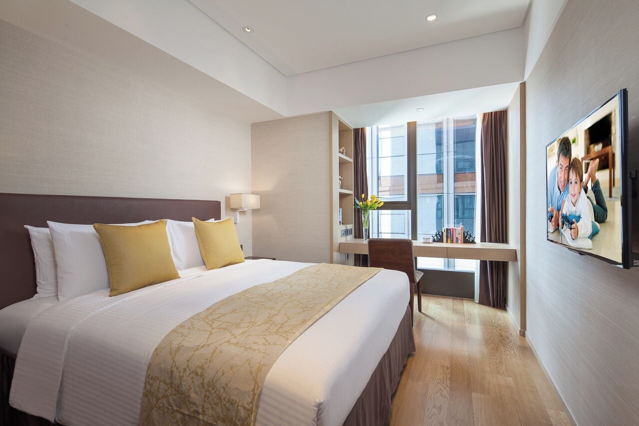A hotel room with a large bed, a desk, and a window with curtains.